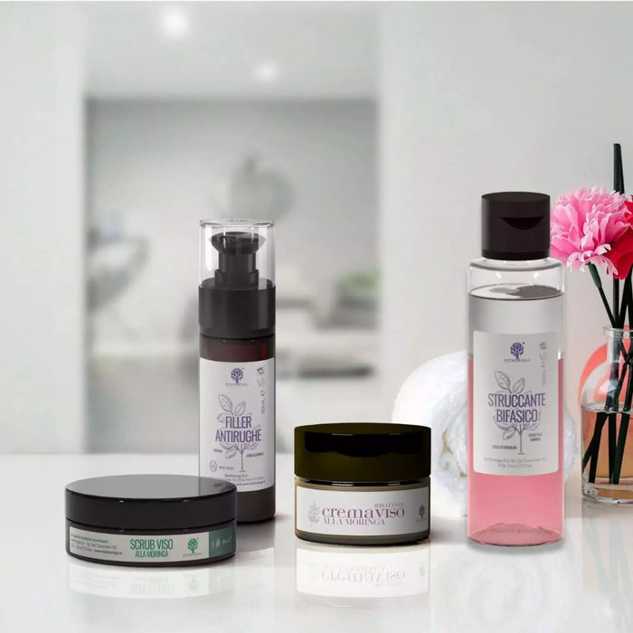 Los cuatro cosméticos del tratamiento facial antiedad RedMoringa con moringa en una repisa del baño con una flor rosa
